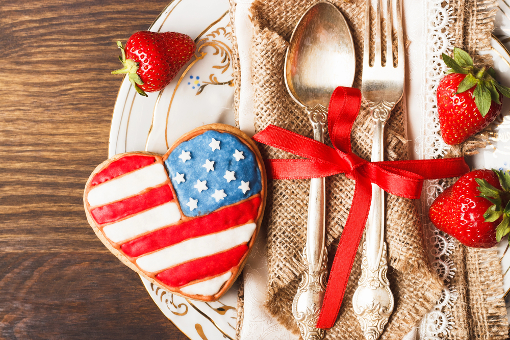 Table set with silver in a red ribbon with red strawberries and an american flag cookie