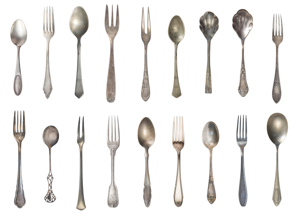 A collage of antique forks and spoons on a white background