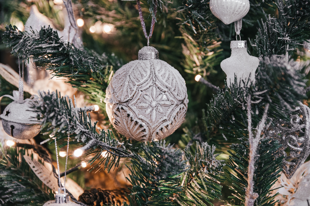 A silver ornament hanging on a festive tree