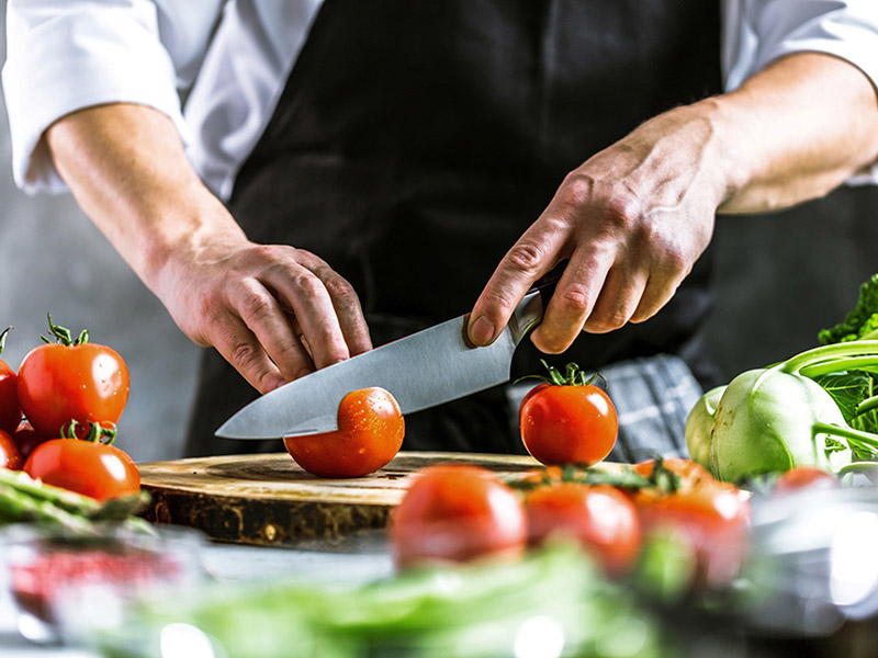 Chef cutting a tomato with a chef knife